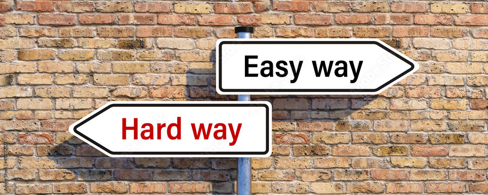 signpost with two arrow-shaped signs with the words HARD WAY and EASY WAY in opposite direction in front of a brick wall signpost with two arrow-shaped signs with the words HARD WAY and EASY WAY in opposite direction in front of a brick wall
