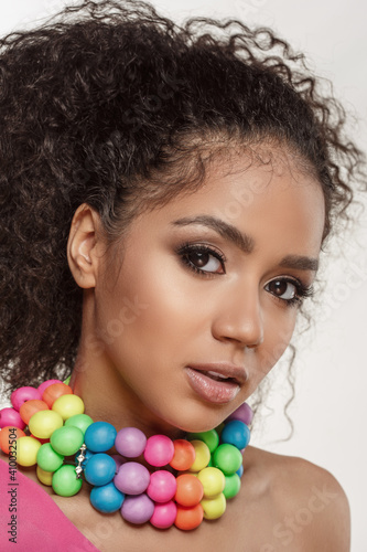 Beauty black skin woman fashion african ethnic female face portrait. Young girl model with afro and extraordinary brightly colored rainbow beads around the neck