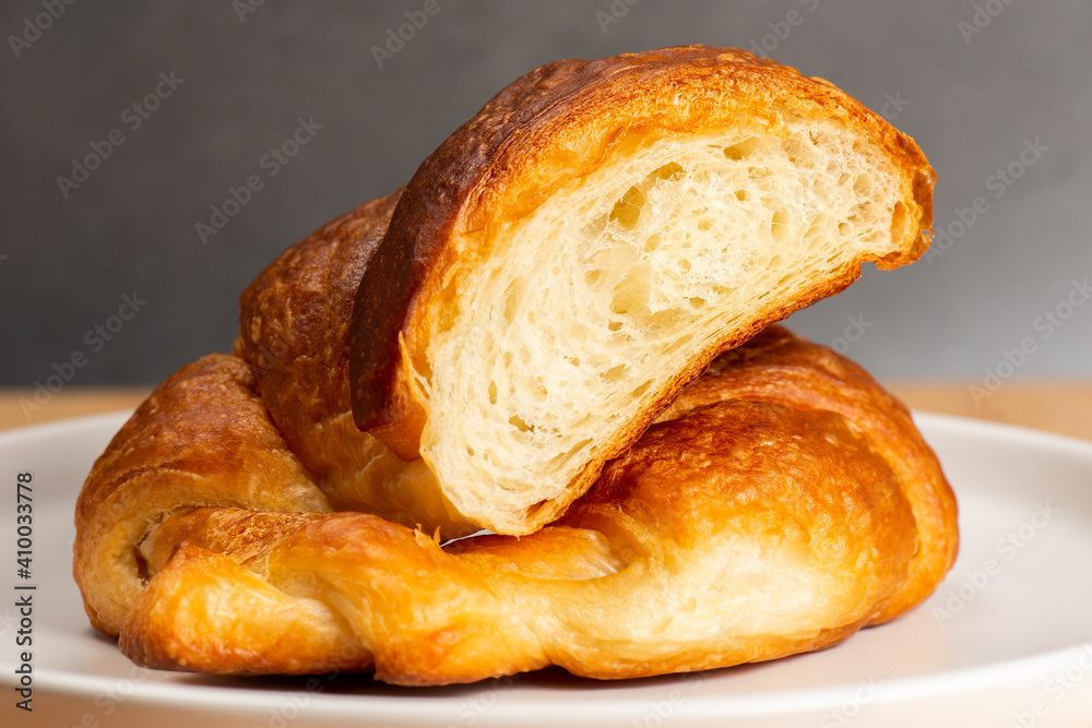 Detailed and closeup photo of a fresh baked plain buttery and flaky croissant.