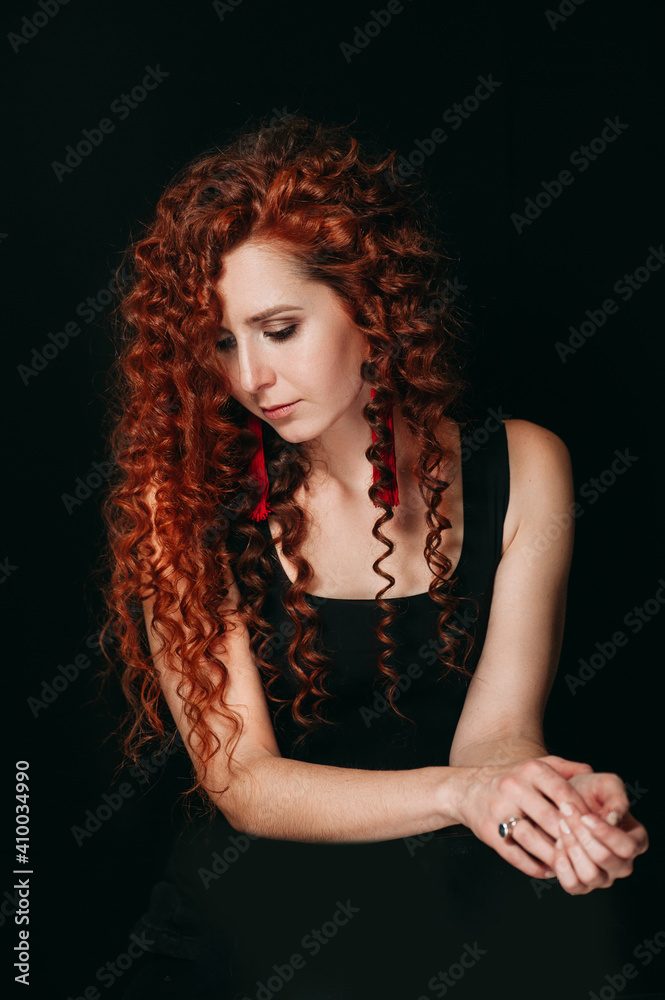 A attractive girl with curly red hair in a black undershirt on a black background A attractive girl with curly red hair in a black undershirt on a black background