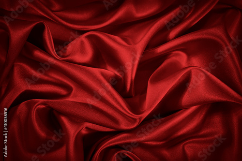  Red silk satin background. Beautiful soft wavy folds on smooth shiny fabric. Anniversary, Christmas, wedding, valentine, event, celebration concept. Red luxury background with copy space for design. 