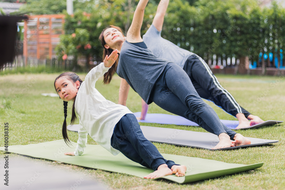 mother, father practicing doing yoga exercises with child daughter outdoors in meditate pose together