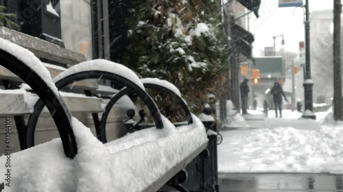 snowy bench in winter blizzard - snowing on cold day, man walking in snow in New York City NYC
