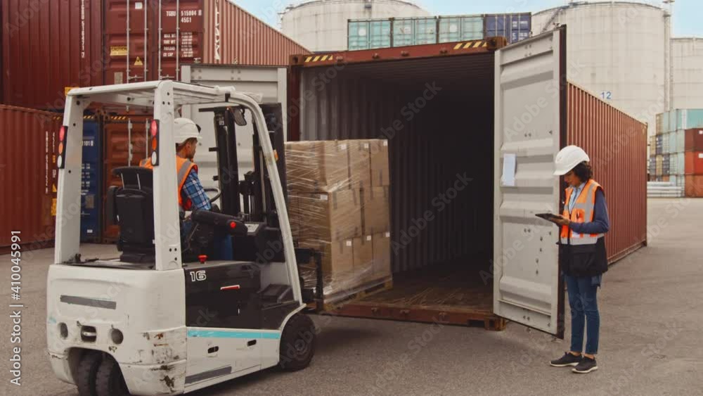 Forklift Driver Loading a Shipping Cargo Container with a Full Pallet with Boxes in Logistics Port Terminal