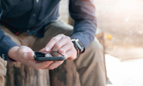 Closeup view of man hands using smartphone while sitting outdoors.