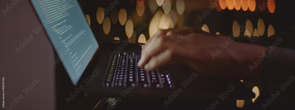 Male hands typing on laptop keyboard in late evening. Selective focus. Software developing concept.