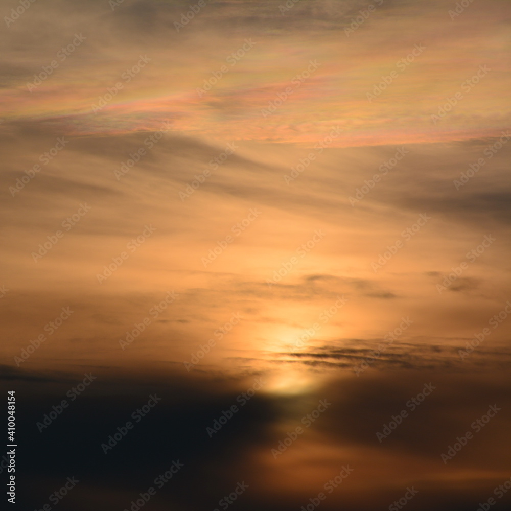 The rising sun paints the clouds in rainbow colors.