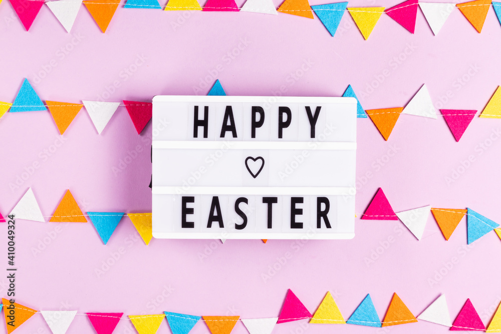 Happy easter lettering on white board with felt garland on pink background Happy easter lettering on white board with felt garland on pink background