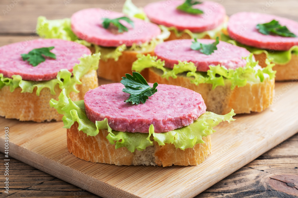 Sandwiches with lettuce leaves and sliced salami sausage on a wooden Board. Sandwiches with lettuce leaves and sliced salami sausage on a wooden Board.