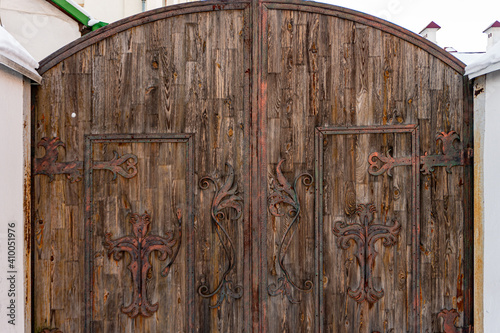 Massive wide antique brown wooden door with hooks and curtains, wooden texture