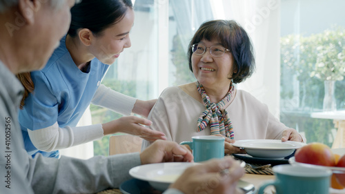 Attractive young senior asian citizen couple happy sit, talk, eat soup for healthy nutrition breakfast meal on dining table at home in morning in routine lifestyle in old asia nursing in-home care.