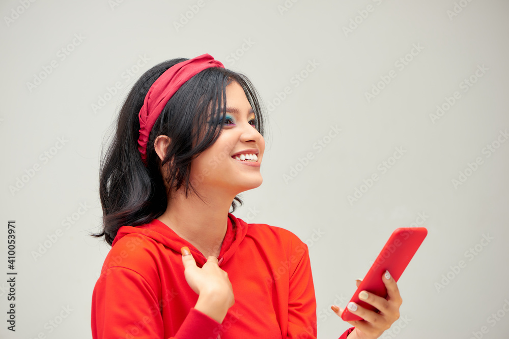 Photo of surprised young woman with bright makeup using smartphone isolated over gray background Photo of surprised young woman with bright makeup using smartphone isolated over gray background