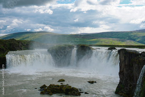 godafoss waterfall in summer cloudy weather, splashes of water rise up, there are beautiful clouds in the sky, nature of Iceland