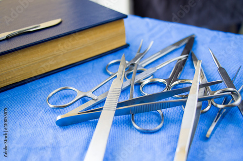 Set of stainless dissecting kits with book on a blue sterile table photo