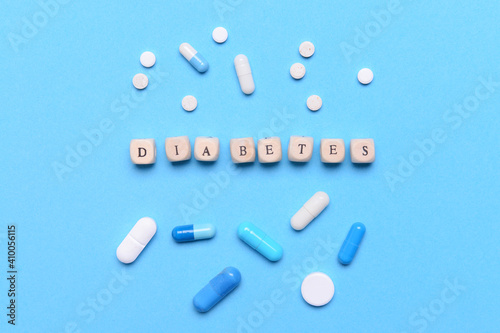 Cubes with word DIABETES and pills on color background