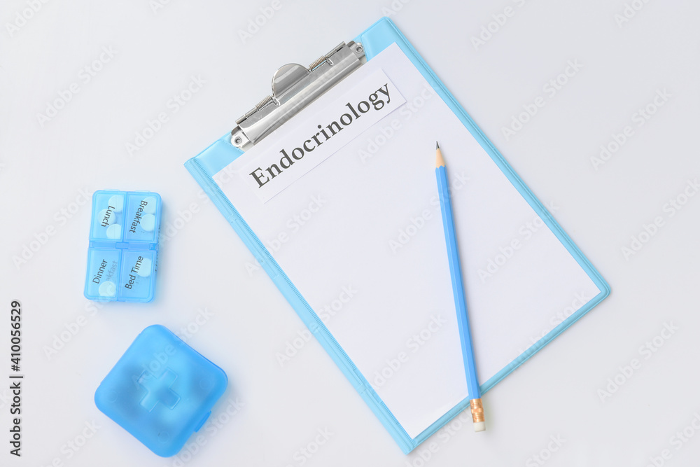 Clipboard with word ENDOCRINOLOGY and pills on white background Clipboard with word ENDOCRINOLOGY and pills on white background