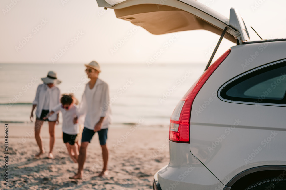 Asian family vacation holiday, Happy family walking on the beach in the sunset.Happy family is walking into the car.Back view of a happy family on a tropical beach and a car on the side. Asian family vacation holiday, Happy family walking on the beach in the sunset.Happy family is walking into the car.Back view of a happy family on a tropical beach and a car on the side.