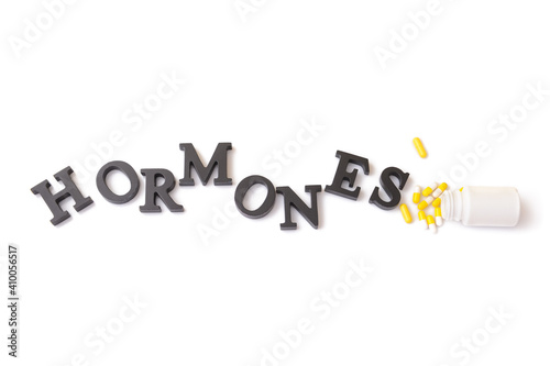 Word HORMONES and pills on white background