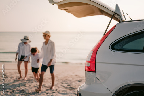 Asian family vacation holiday, Happy family walking on the beach in the sunset.Happy family is walking into the car.Back view of a happy family on a tropical beach and a car on the side.