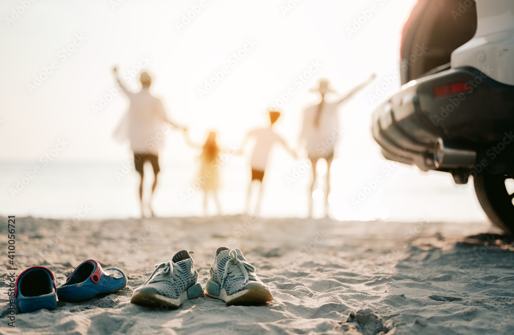 Close up on the shoes.Family vacation holiday, Happy asian family running on the beach in the sunset. Back view of a happy family on a tropical beach and a car on the side. - obrazy, fototapety, plakaty 