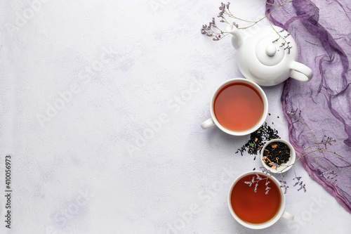 Composition with teapot and cups of tea on light background