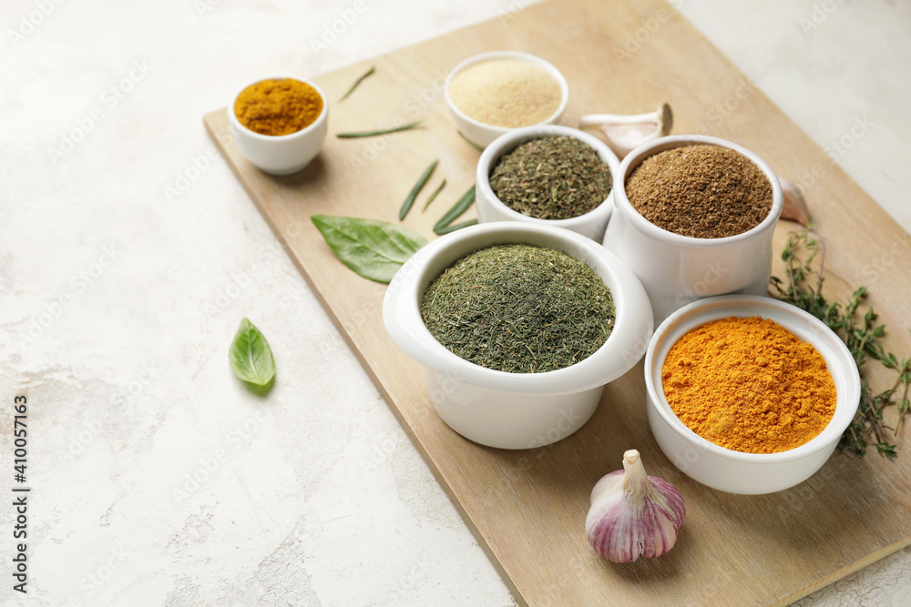 Board with different spices and herbs on light background Board with different spices and herbs on light background