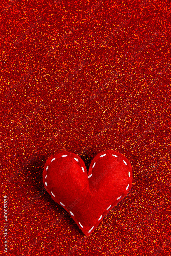 Handmade soft stitched felt heart on red shiny background, sequins in the side. The concept for Valentine's Day. Copy space. Handmade soft stitched felt heart on red shiny background, sequins in the side. The concept for Valentine's Day. Copy space.