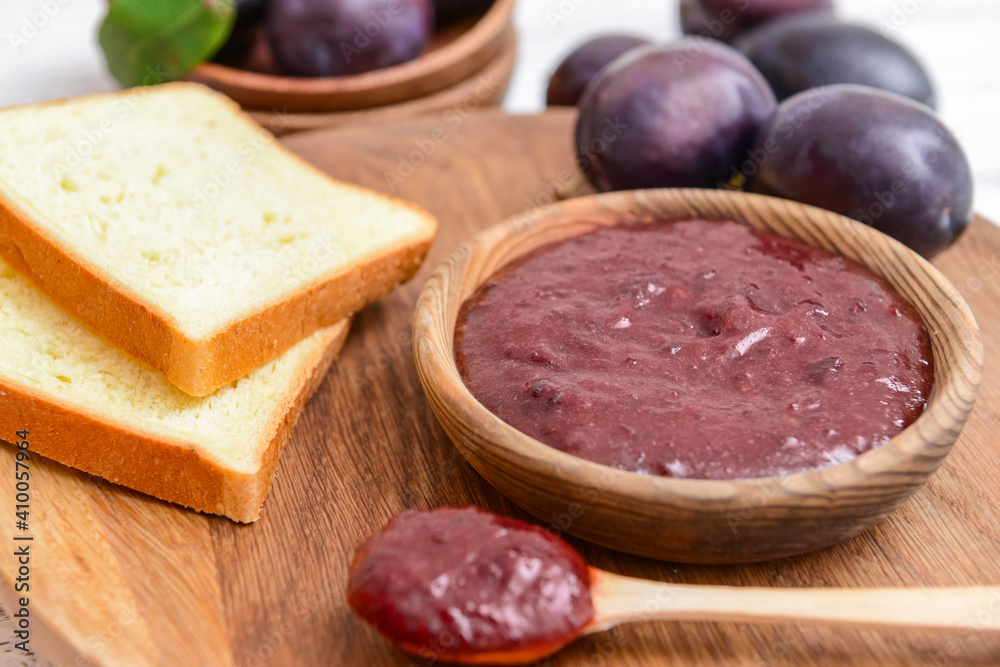 Bowl with delicious homemade plum jam on wooden board Bowl with delicious homemade plum jam on wooden board