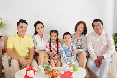 Happy big Vietnamese family sitting on sofa in living room when celebrating Lunar New Year at home