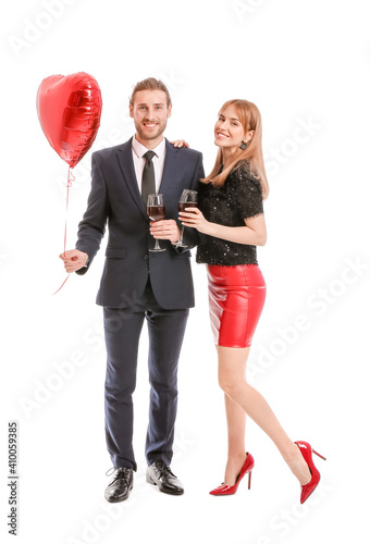 Young couple with glasses of wine and air balloon on white background. Valentine's Day celebration