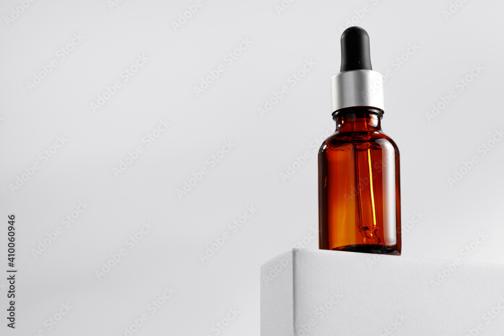 Essential oil bottle on gray block against gray background