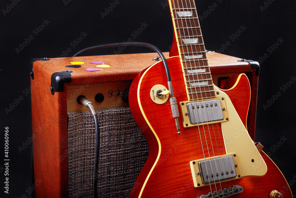 Combo amplifier for electric guitar with guitar on black background.
