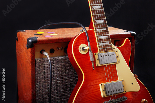 Combo amplifier for electric guitar with guitar on black background.