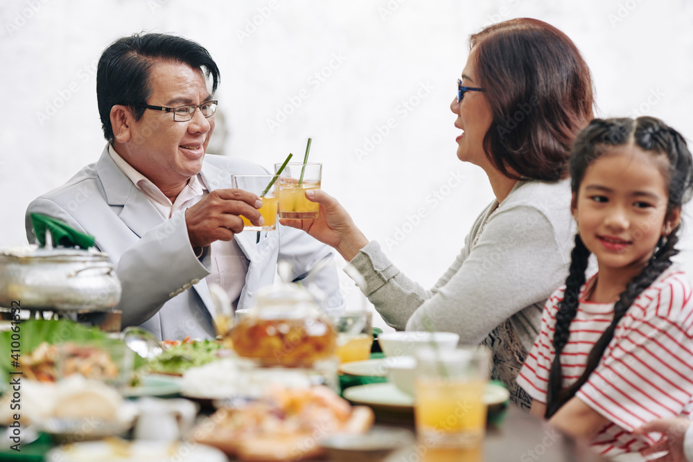 Married senior couple toasting with glasses of juice when talking at family dinner Married senior couple toasting with glasses of juice when talking at family dinner