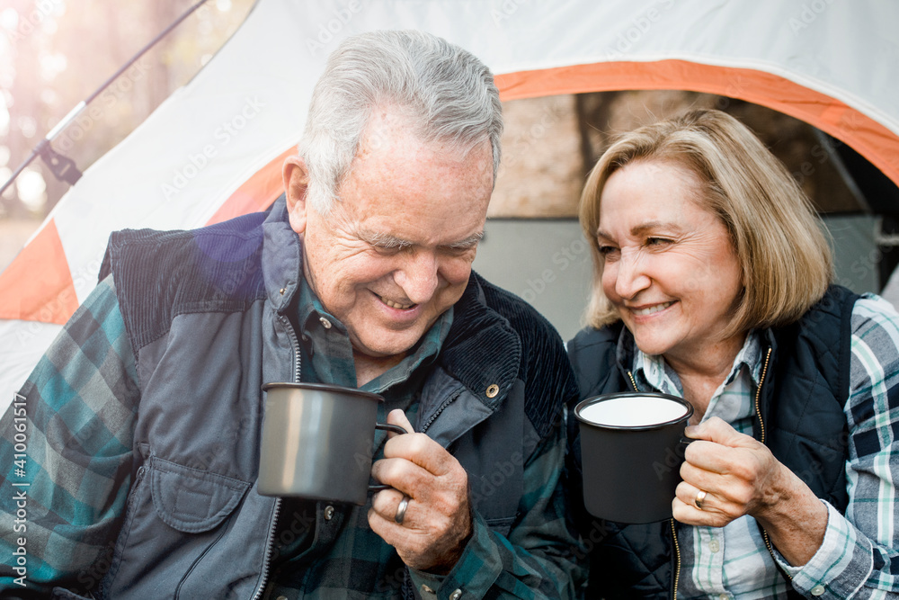 Happy old couple having coffee by the tent in the forest Happy old couple having coffee by the tent in the forest