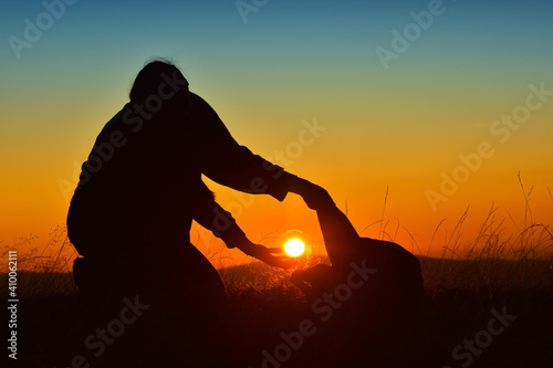 Silhouette of woman trying to put the sun inside a bag