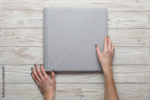 person touch and looking photobook. Family photoalbum on the table.womans hand holding a grey family photo album with copy space for text. stylish wedding photo album on light background photo