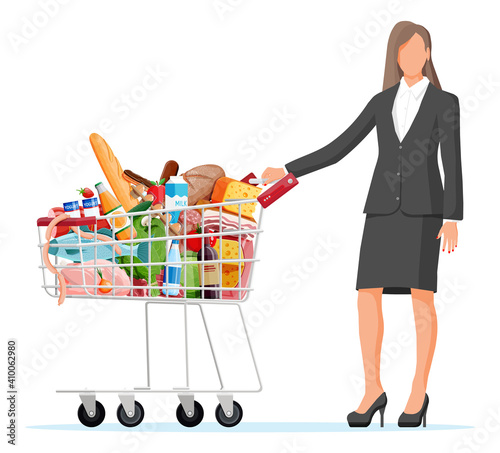 Woman with shopping cart full of fresh products. Grocery store supermarket. Food and drinks. Milk, vegetables, meat, chicken cheese, sausages, salad, bread cereal steak egg. Flat vector illustration