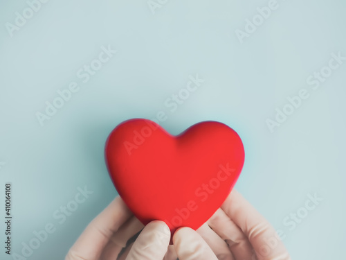 Doctor's hands in medical gloves with red heart, health insurance, organ donation, charity during the covid-19 coronavirus pandemic, life saving, heart health, World Heart Day, Medical banner