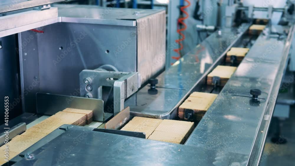 Factory machinery is relocating waffle bars in batches. Production line with waffles. Factory machinery is relocating waffle bars in batches. Production line with waffles.
