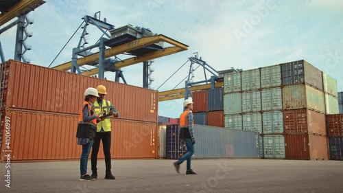 Multiethnic Female Industrial Engineer with Tablet and Black African American Male Supervisor in Hard Hats Stand in Container Terminal photo