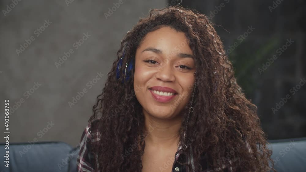 Portrait of playful carefree attractive black woman in wireless headphones posing indoors, looking with friendly cheerful smile, expressing natural beauty, positive vibes, happiness and excitement. Portrait of playful carefree attractive black woman in wireless headphones posing indoors, looking with friendly cheerful smile, expressing natural beauty, positive vibes, happiness and excitement.