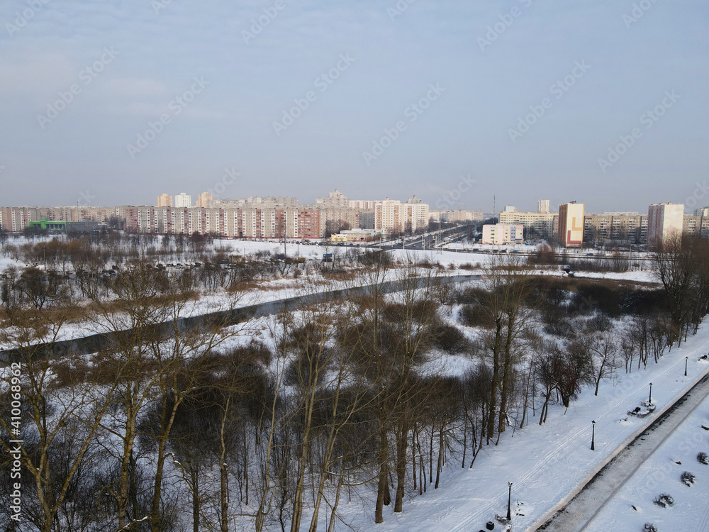 Obraz premium Urban winter landscape from above. Multi-storey buildings and trees in the city park are visible.