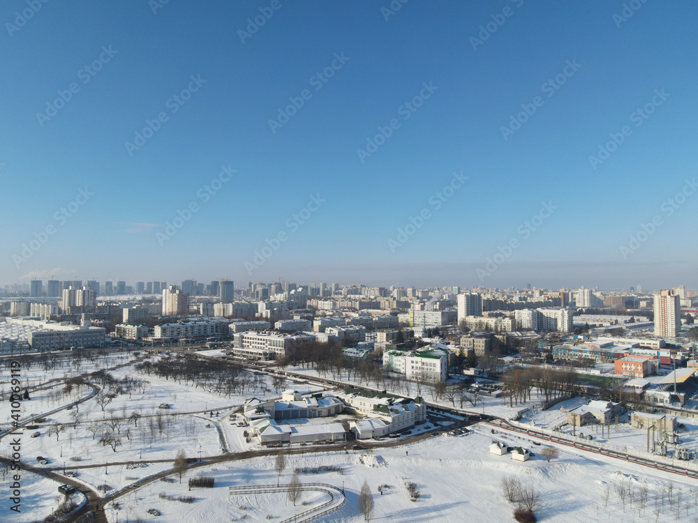 Obraz premium Urban winter landscape from above. Multi-storey buildings and trees in the city park are visible.