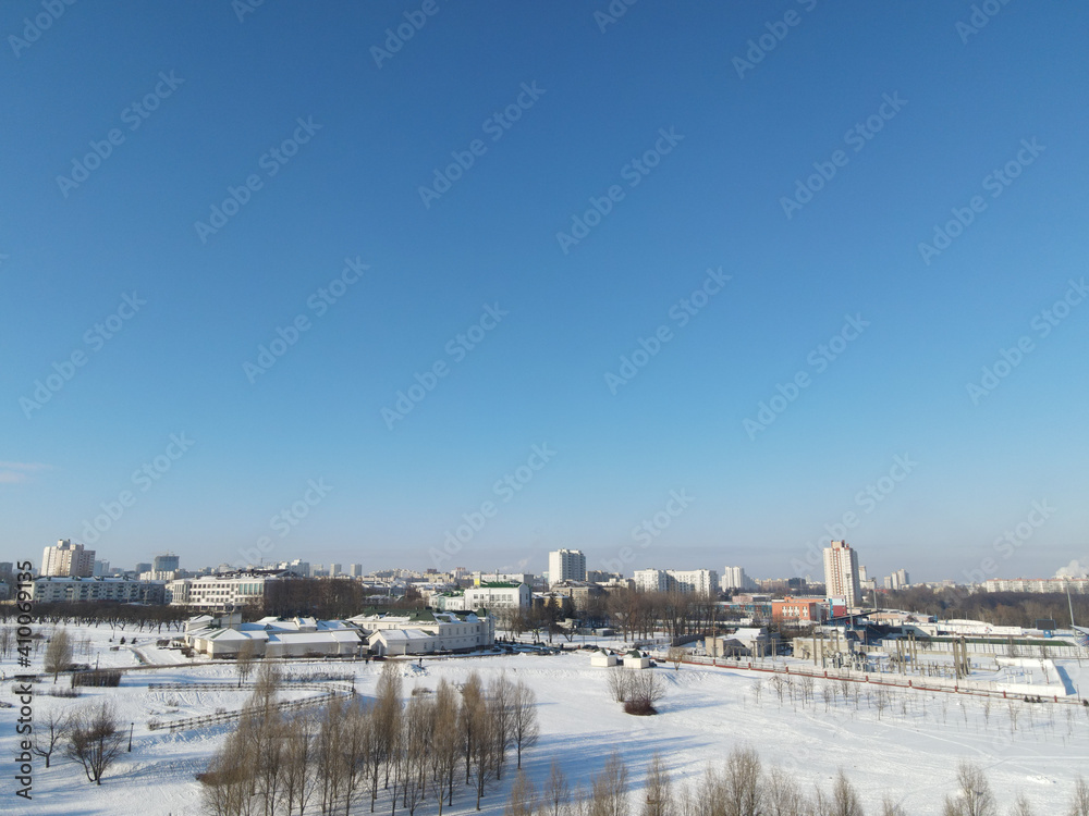 Urban winter landscape from above. Multi-storey buildings and trees in the city park are visible.