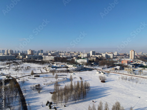 Urban winter landscape from above. Multi-storey buildings and trees in the city park are visible.