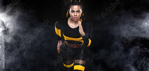 Strong athletic woman sprinter, running on black background wearing in the sportswear. Fitness and sport motivation. Runner concept. © Mike Orlov