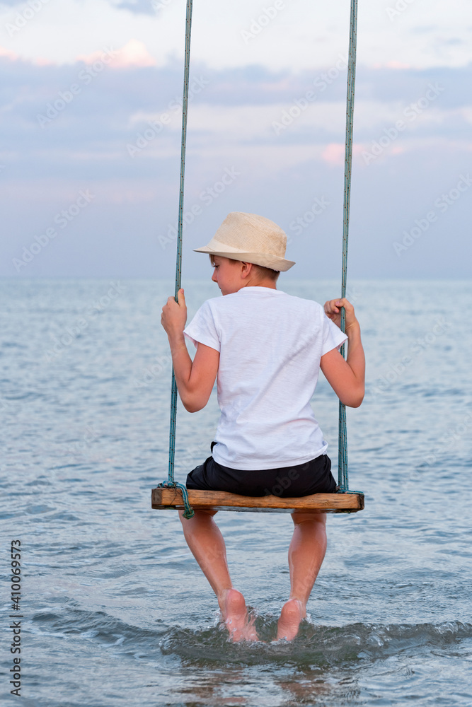 Portrait of boy on swing in the water back view. Vertical frame. Portrait of boy on swing in the water back view. Vertical frame.