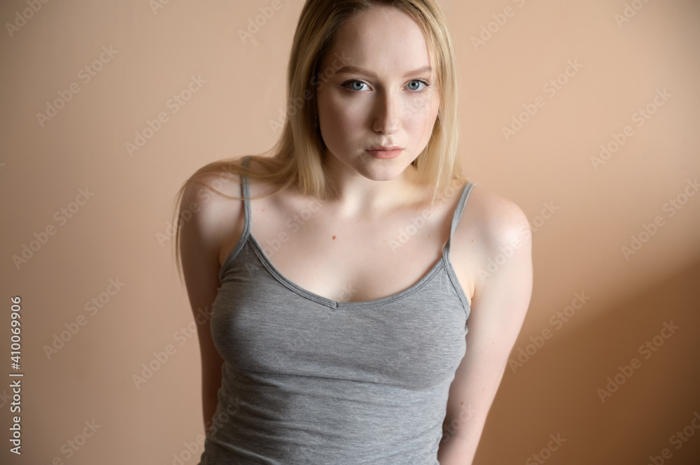 Graceful young woman posing against beige wall. Graceful young woman posing against beige wall.