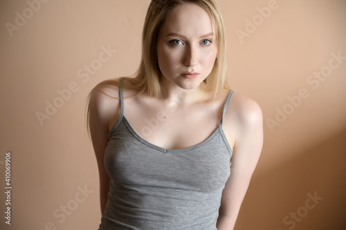 Graceful young woman posing against beige wall.